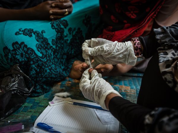 Habiba Suleiman, 29, a district malaria surveillance officer, sits down with the children of a family she tested for malaria. USAID