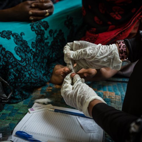 Habiba Suleiman, 29, a district malaria surveillance officer, sits down with the children of a family she tested for malaria. USAID